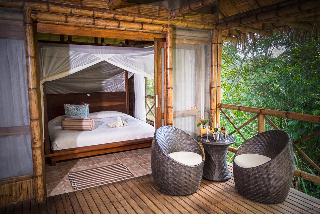 Chambre en bambou avec lit à moustiquaire et terrasse privée face à la forêt amazonienne équatorienne
