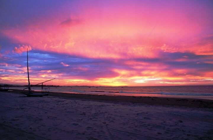 Coucher de soleil rose et orange sur la plage de Flecheiras avec un voilier traditionnel