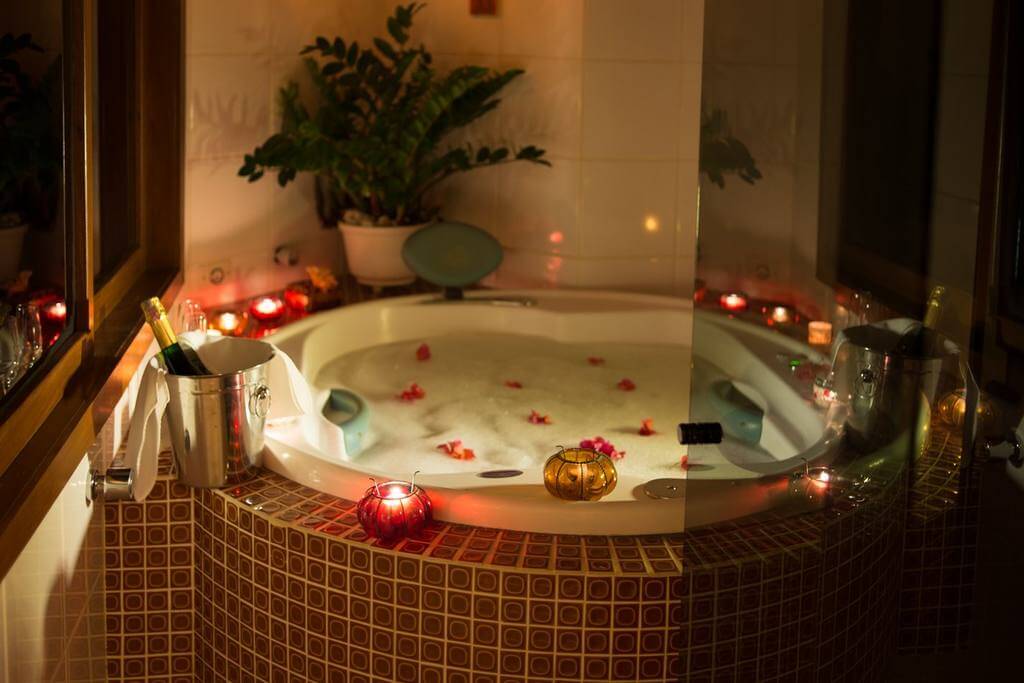 Baignoire romantique avec bougies, pétales et bouteille de champagne, hôtel à Boipeba, Brésil