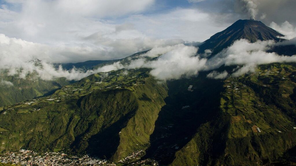 Vue aérienne du volcan Tungurahua en éruption dominant la vallée verdoyante de Baños, Équateur