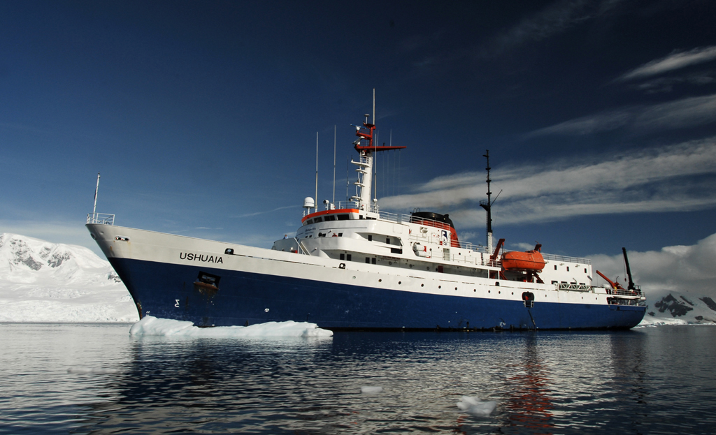 Navire d'expédition Ushuaia ancré sur des eaux calmes près de montagnes enneigées en Antarctique