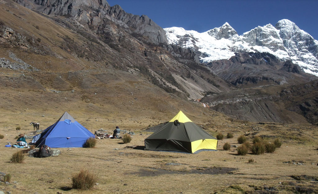 Camp de tentes bleue et jaune dans une vallée près des sommets enneigés du Huantsan, Pérou