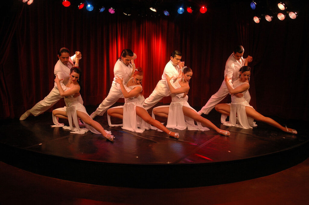 Quatre couples de danseurs de tango en costumes blancs se produisent sur scène à Buenos Aires