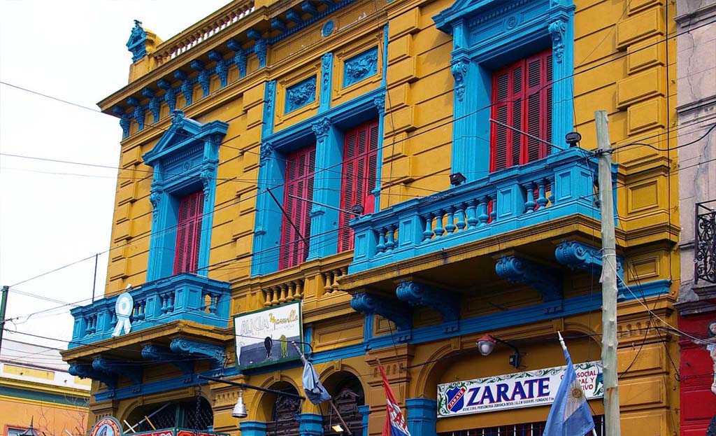 Façade jaune ornée de balcons bleus et fenêtres rouges dans le quartier La Boca, Buenos Aires