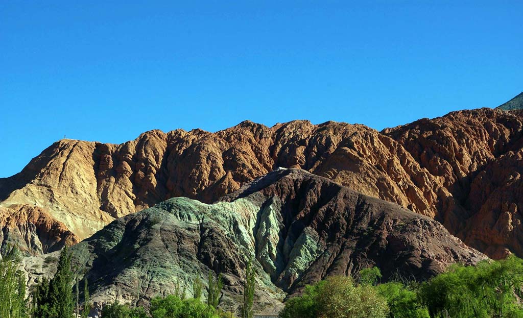 Montagne aux sept couleurs sous ciel bleu, végétation verte au premier plan, Purmamarca, Argentine