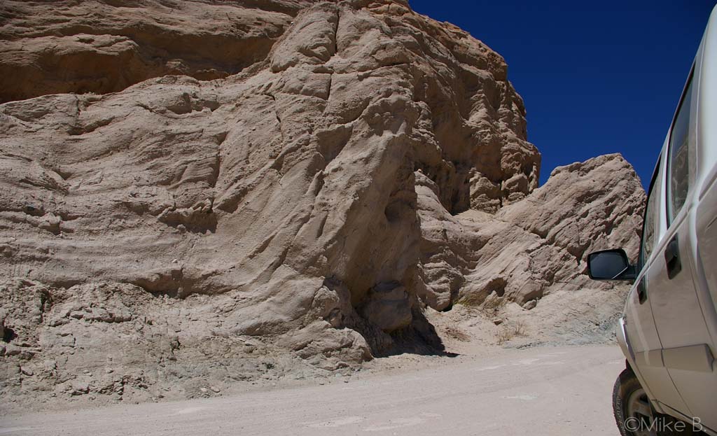 Formation rocheuse érodée bordant une piste, véhicule tout-terrain garé, région de Cachi, Argentine