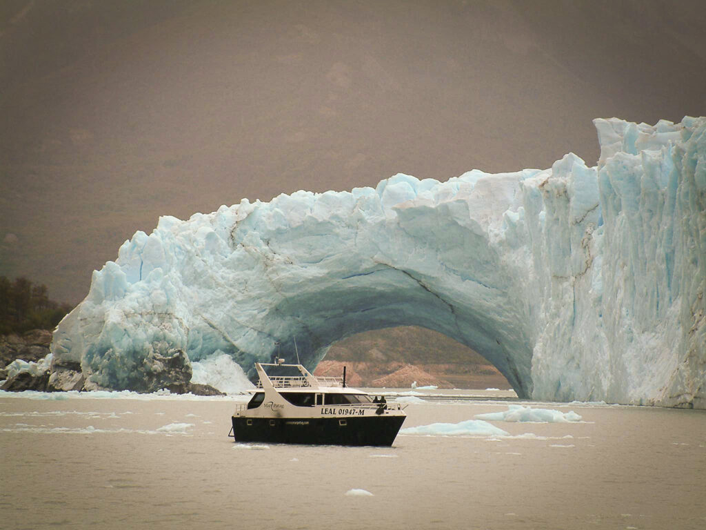 Bateau d'excursion passant devant une arche de glace du glacier près d'El Calafate, Argentine