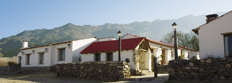 Bâtiment blanc à toit rouge avec montagnes en arrière-plan à Tafi del Valle, Argentine