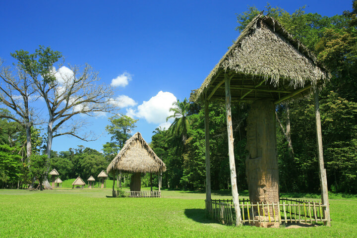 Stèles mayas de Quirigua abritées sous des toits de chaume dans un parc verdoyant, Guatemala