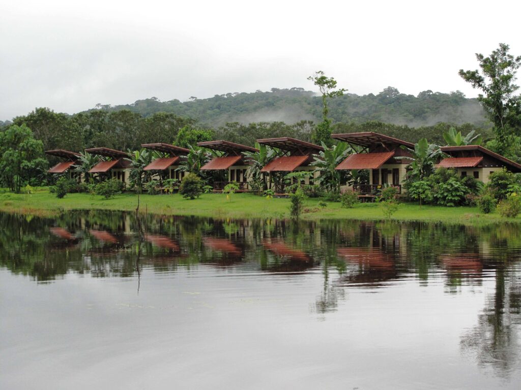 Bungalows à toits rouges en bord de lagune face à la forêt tropicale à Boca Tapada, Costa Rica