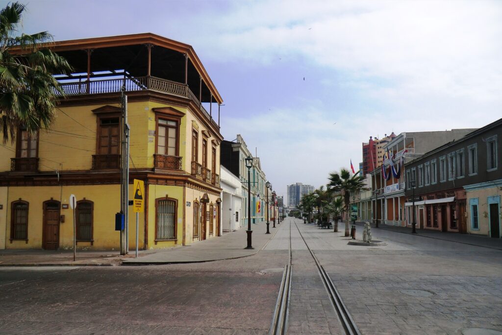 Rue historique d'Iquique avec bâtiments coloniaux colorés et voie de tramway au sol