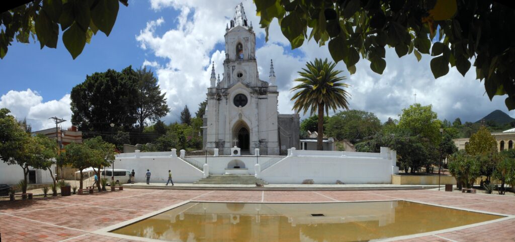Église blanche de style néogothique avec place pavée et bassin d'eau, région d'Oaxaca