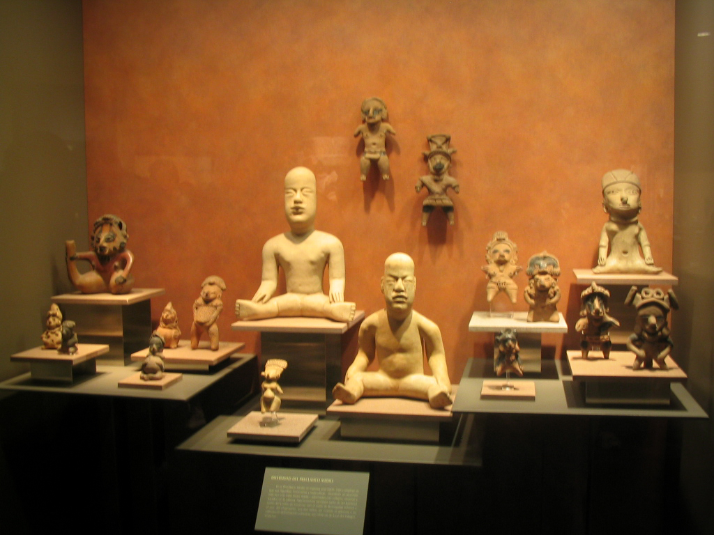 Figurines précolombiennes en argile exposées sur socles contre un mur orange, musée d'anthropologie, Mexique