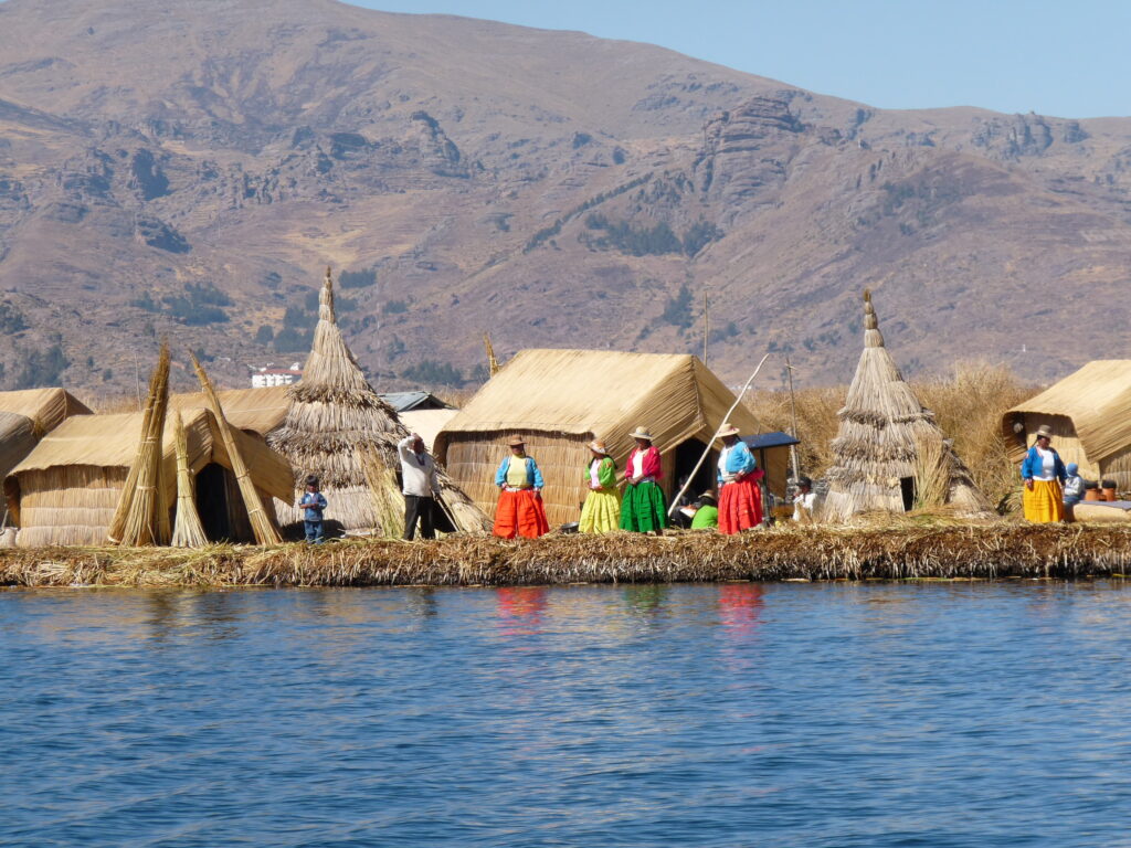 Habitants uros en habits colorés devant des huttes en roseaux, île flottante du lac Titicaca, Pérou