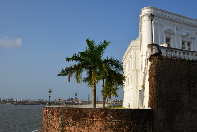 Bâtiment blanc colonial en bord de mer avec palmiers et rempart en pierre, Sao Luis, Brésil