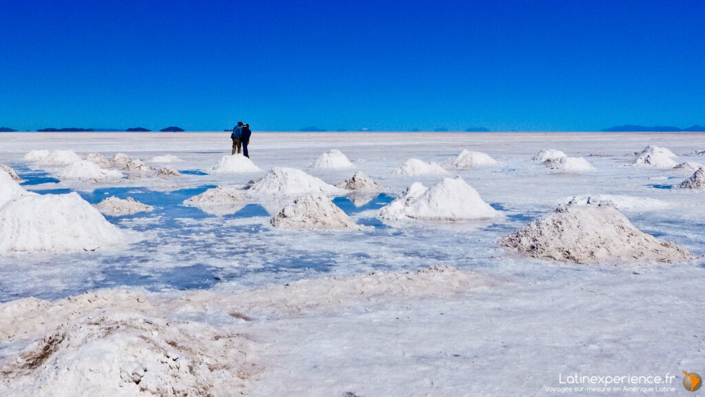 Deux voyageurs près de monticules de sel en cours de récolte dans le Salar d'Uyuni, Bolivie