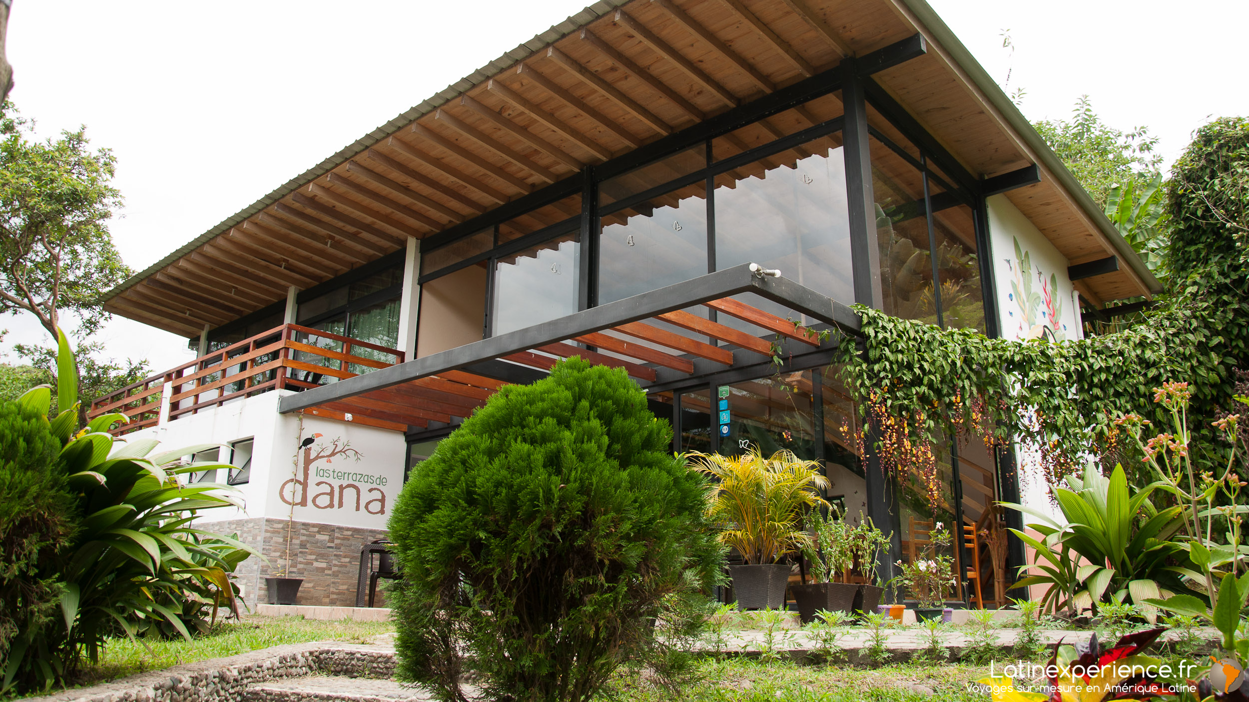 Façade en bois et verre du lodge Las Terrazas de Dana entourée de végétation luxuriante en Équateur