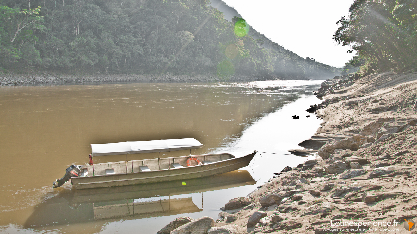Pirogue à toit amarrée sur une rive rocheuse d'un fleuve en Amazonie péruvienne