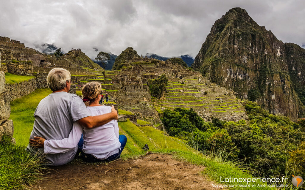 Couple enlacé admirant les ruines et terrasses du Machu Picchu, Pérou, avec le Huayna Picchu en arrière-plan