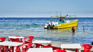 Bateau jaune amarré près d'une plage avec terrasse de restaurant
