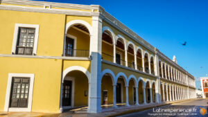 Bâtiment colonial jaune avec arcades blanches sous ciel bleu au Yucatan