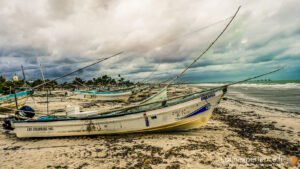 Bateaux de pêche échoués sur une plage du Yucatan sous ciel orageux