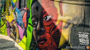 Fresque murale colorée représentant un visage masqué en street art urbain