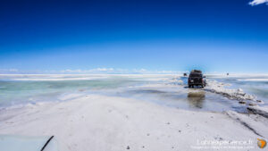 Véhicule 4x4 traversant le Salar d'Uyuni en Bolivie sous ciel bleu