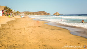 Plage de sable doré avec palmiers et baigneurs au Mexique