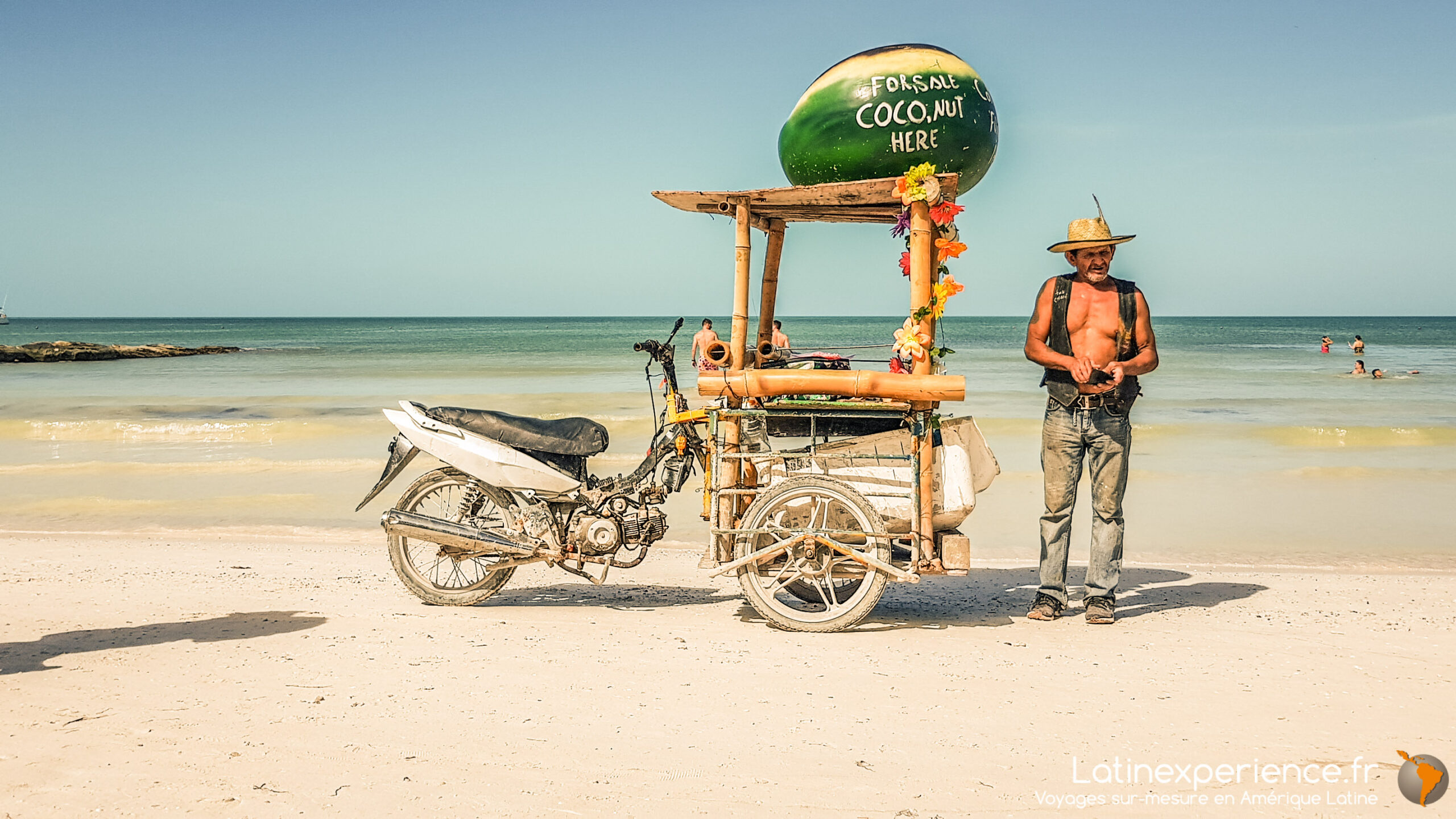 Vendeur de noix de coco avec sa moto-triporteur sur une plage de sable mexicaine