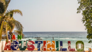 Panneau coloré San Agustinillo devant plage tropicale avec palmiers au Mexique