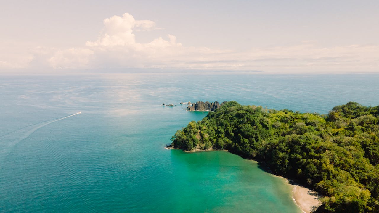 Vue aérienne d'une côte forestière du Costa Rica avec baie turquoise et bateau au large