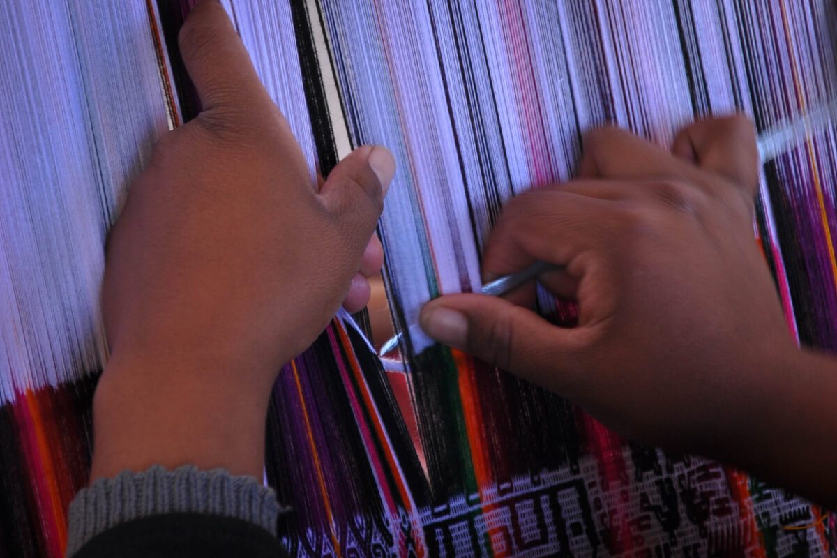 Mains d'une tisseuse manipulant des fils colorés sur un métier à tisser traditionnel, Sucre, Bolivie
