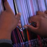 Mains d'une tisseuse manipulant des fils colorés sur un métier à tisser traditionnel, Sucre, Bolivie