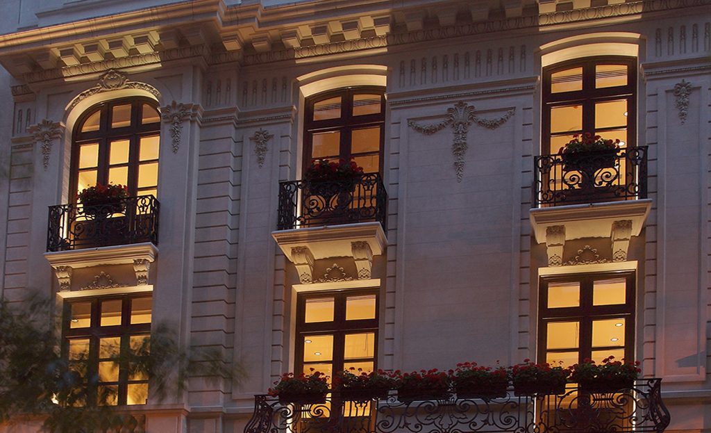 Façade d'un immeuble ancien à Buenos Aires, balcons en fer forgé fleuris illuminés le soir