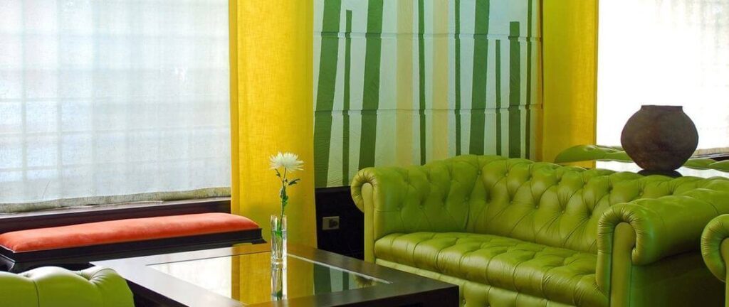 Salon d'hôtel à Santiago du Chili avec canapé en cuir vert et rideaux jaunes colorés