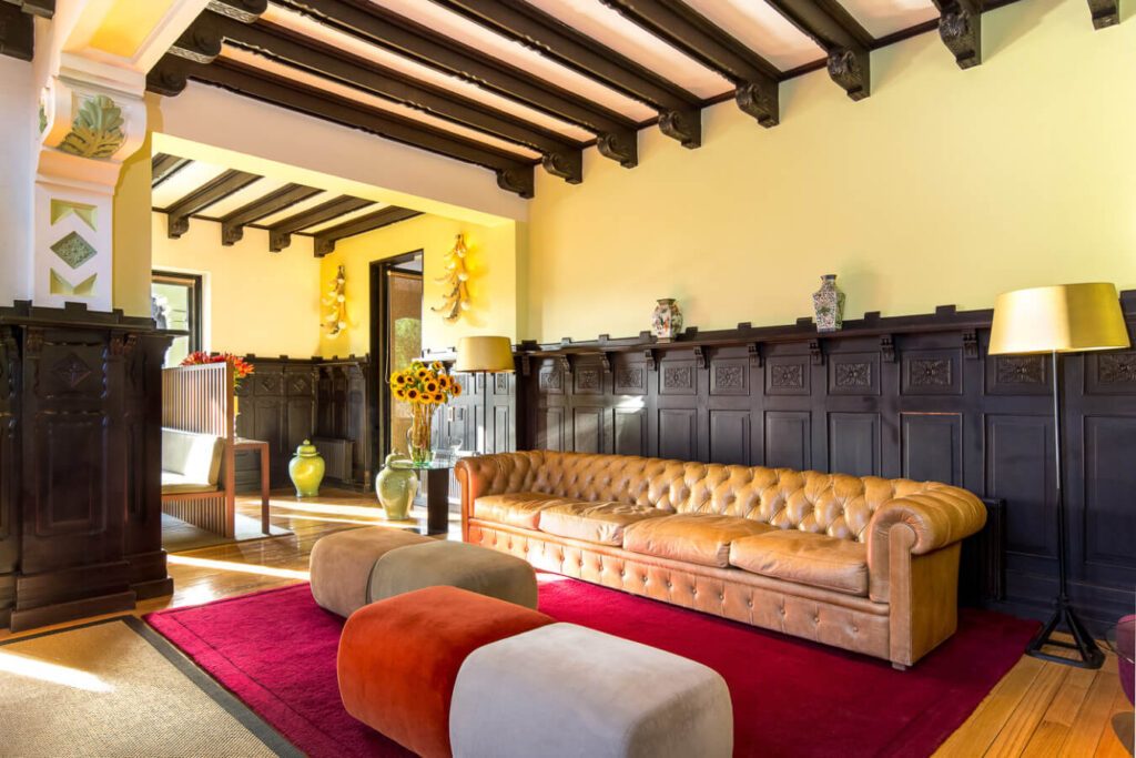 Salon d'hôtel au Chili avec canapé chesterfield en cuir, boiseries sombres sculptées et tapis rouge