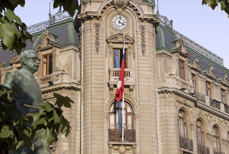 Bâtiment historique avec tour horloge et drapeau chilien, statue en bronze à Santiago, Chili