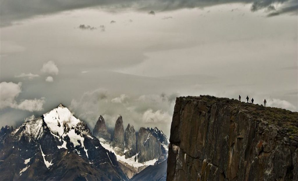 Randonneurs debout au sommet d'une falaise face aux tours de granit de Torres del Paine, Patagonie chilienne