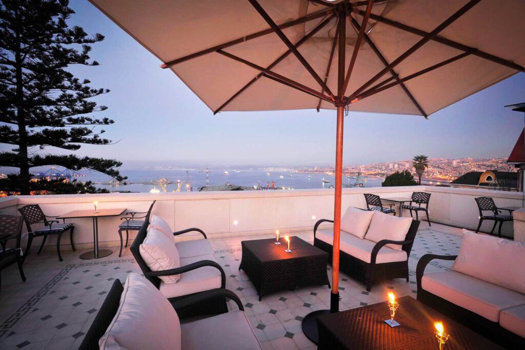 Terrasse lounge avec parasol surplombant la baie et le port de Valparaiso au crépuscule, Chili