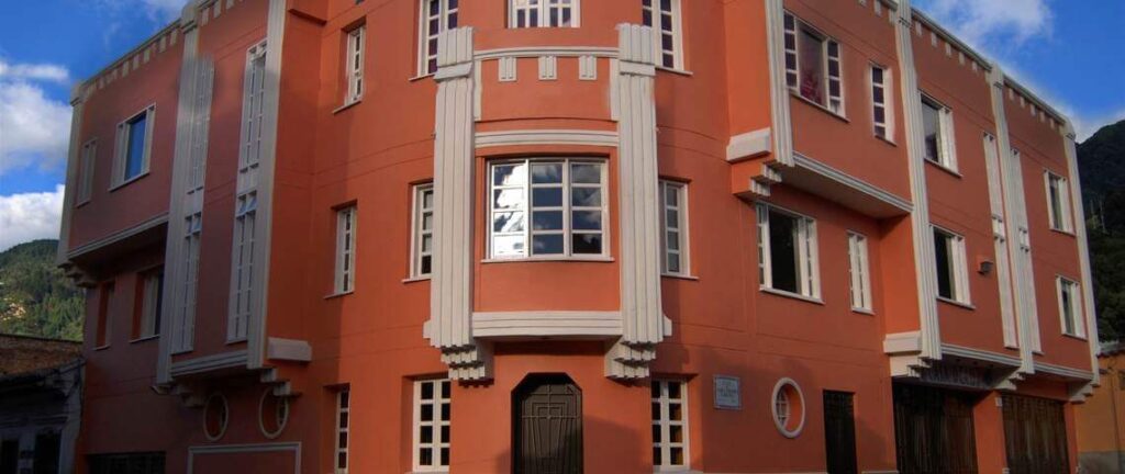 Façade orange Art déco d'un immeuble à Bogotá, Colombie, avec fenêtres blanches et montagnes en arrière-plan