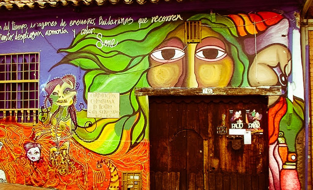 Fresque murale colorée avec visage et personnage squelette au-dessus d'une porte en bois, Bogota, Colombie