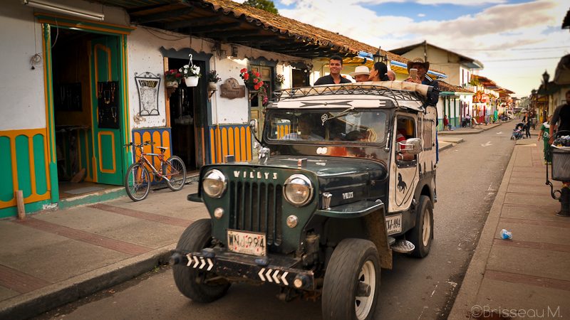 Jeep Willys traditionnelle chargée de passagers dans une rue colorée de Salento, Colombie