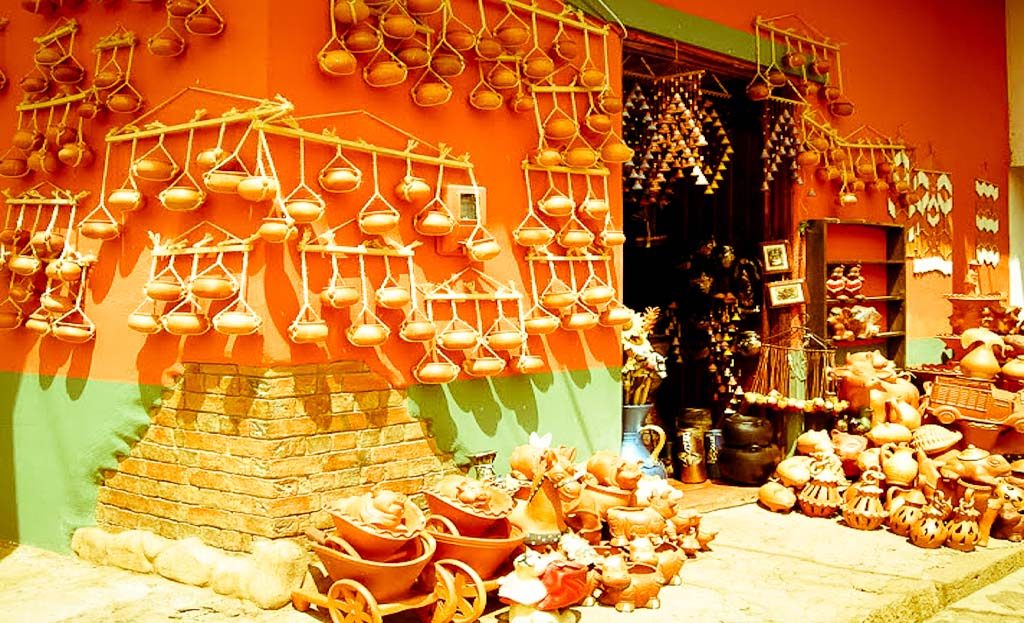 Boutique d'artisanat en Colombie avec poteries en terre cuite suspendues sur mur orange à Villa de Leyva