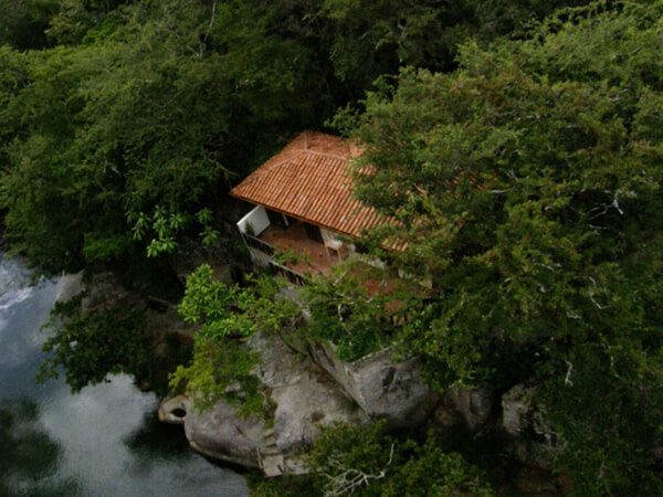 Vue aérienne d'une cabane au toit de tuiles surplombant une rivière, forêt tropicale au Costa Rica