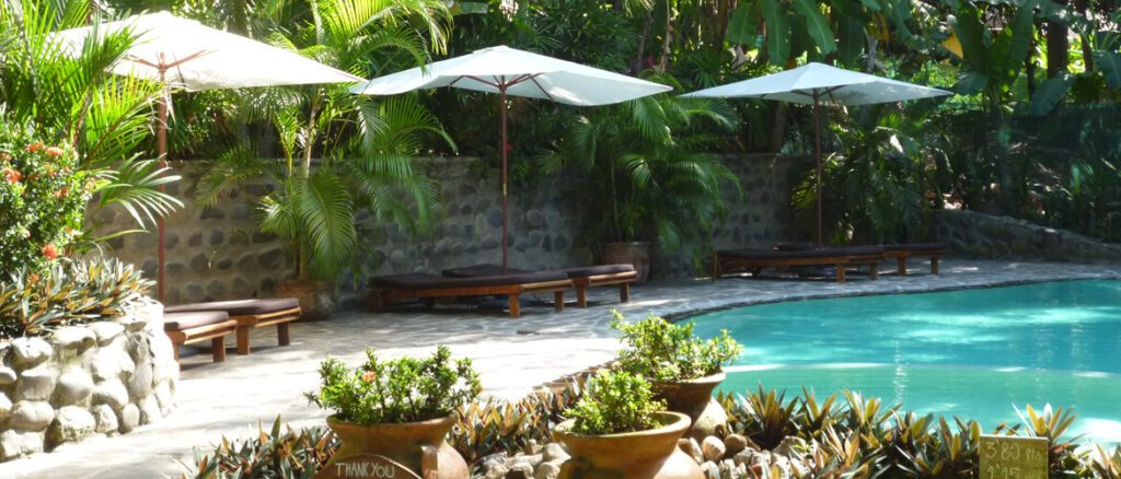Piscine d'hôtel entourée de palmiers avec transats et parasols, péninsule de Nicoya, Costa Rica