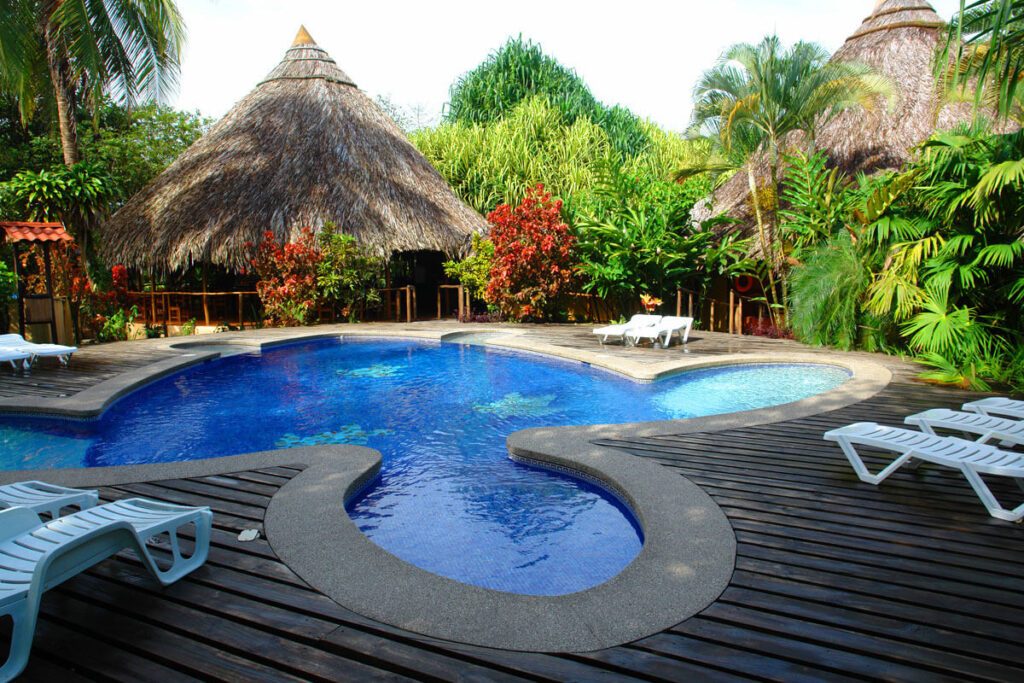 Piscine sinueuse avec transats et toits de chaume dans un lodge tropical à Tortuguero, Costa Rica