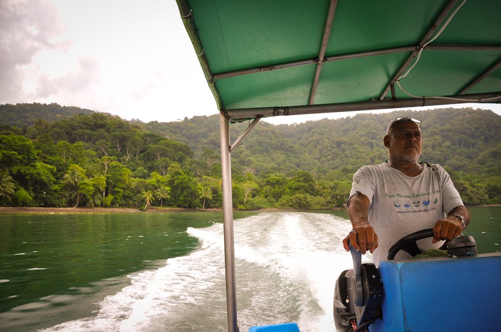 Homme pilotant un bateau devant la forêt tropicale du Golfo Dulce, Costa Rica