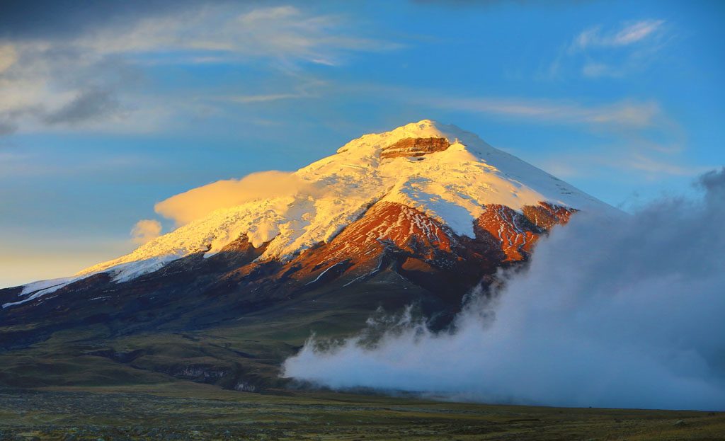 Volcan Cotopaxi enneigé au lever du soleil entouré de nuages, Equateur