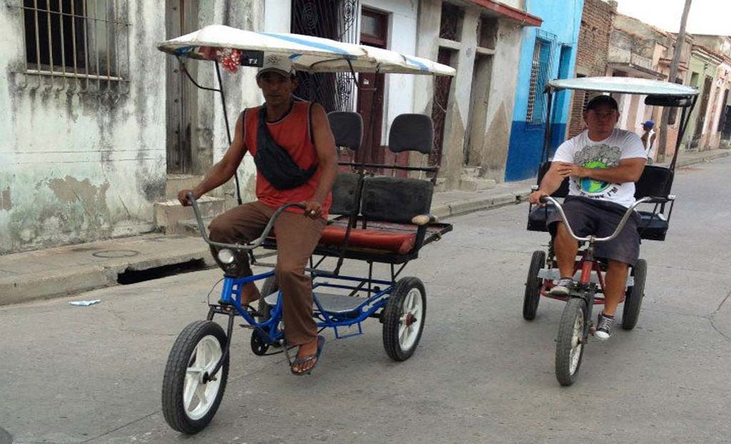 Deux bici-taxis à pédales conduits par des hommes dans une rue de Camagüey, Cuba